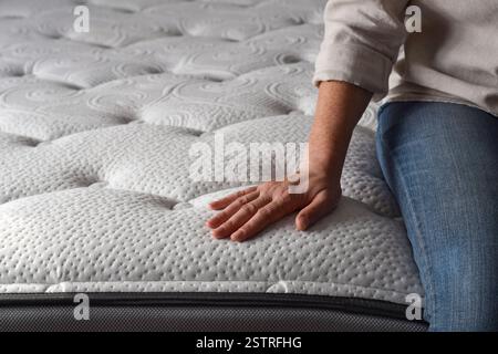 Woman sitting on a brand new mattress and touching the fabric with copy space Stock Photo