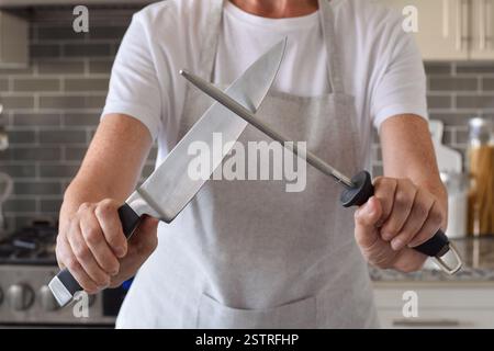 Woman is sharpening a knife in a kitchen at home Stock Photo