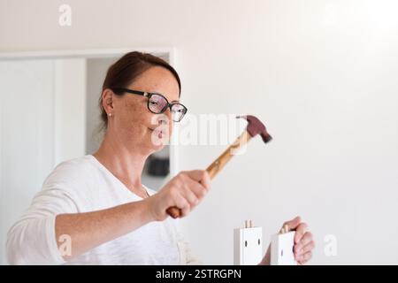 Woman using a hammer to assemble furniture Stock Photo