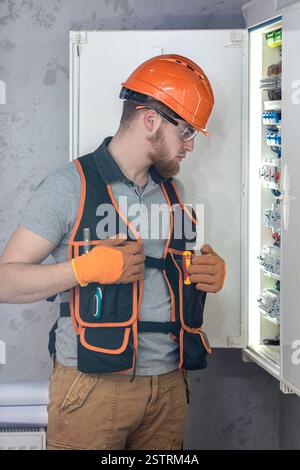 Electrician man in overalls works in the switchboard. Portrait of an electrician in overalls. Stock Photo