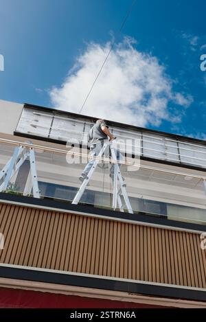Workmen on a ladder installing a new store sign. Stock Photo