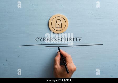 A hand underlining the word CYBERSECURITY with a lock icon above it, symbolizing online safety and data protection on a blue wooden background. Stock Photo