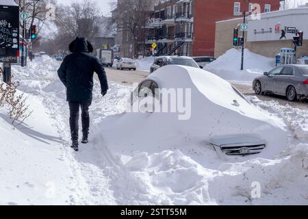 Montreal, Canada - 19 February 2025: Man walking on a sidewalk covered with snow  after major winter storm Stock Photo