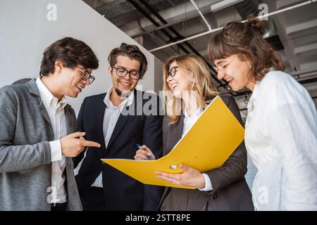 Group of inspired young people standing and discussing new project Stock Photo