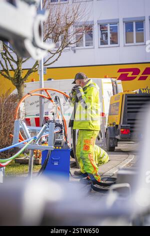 Workers in yellow clothing doing cable work next to vehicles, Wend Glasfasermontage installing conduits for fibre optic cables, Messkirch, district of Stock Photo