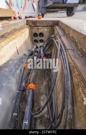 View into an open shaft with cables and pipes at a construction site, Wend Glasfasermontage during the installation of conduits for fibre optic cables Stock Photo