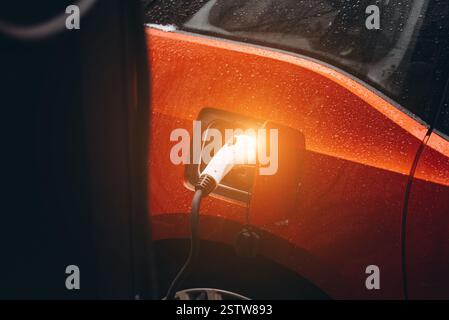 Electric car with power cable supply plugged in Stock Photo