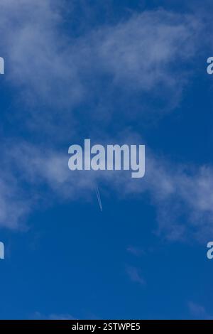 A beautiful blue Sky with a few clouds and an far away airplane in the distance Stock Photo