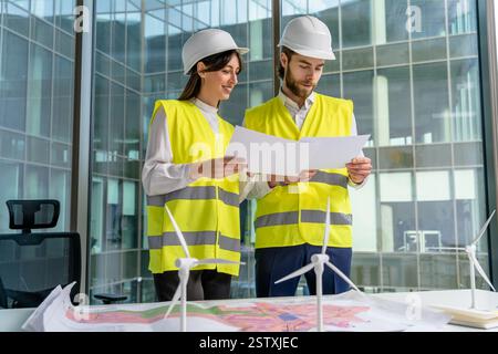 Two young engineers in yellow vests discussing new sustainability project Stock Photo
