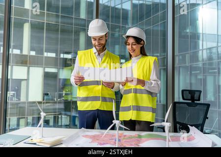 Two young engineers in yellow vests discussing new sustainability project Stock Photo