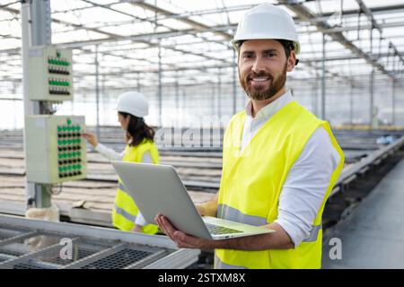 Young male engineer with a laptop checking the parameters at the construction site Stock Photo