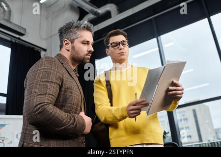 Two colleagues in formal attire review documents during onboarding in a modern office. Stock Photo