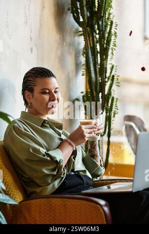 Relaxed atmosphere envelops a young woman as she sips coffee, focused on her laptop screen. Stock Photo