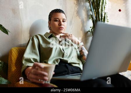 A young woman sips her coffee while working on her laptop in a cozy cafe atmosphere. Stock Photo