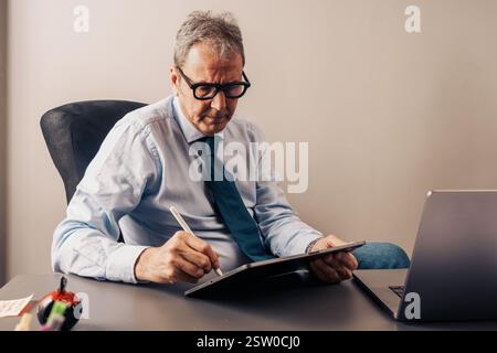 Senior executive working on a tablet with a stylus in a modern office. Concept of digital planning, strategy, leadership, consulting, and workflow opt Stock Photo