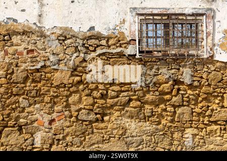 Closeup​ pattern​ of​ surface brick​ wall​ concrete plaster​ for​ vintage​ background. Colors ocher, white, grey. Window left. Stock Photo