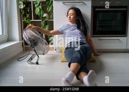 Tired overheated young Asian woman suffering from heat at home Stock Photo