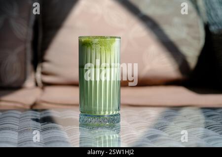 A refreshing green tea latte sits on a table bathed in sunlight Stock Photo