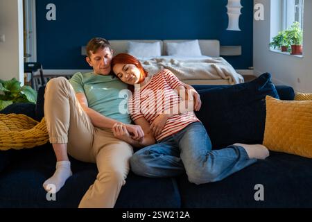 Affectionate middle aged affectionate family couple hugging sitting on couch at home. Stock Photo