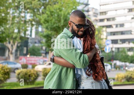 Happy African American couple, students hugging each other goodbye, cuddling as greeting outside Stock Photo
