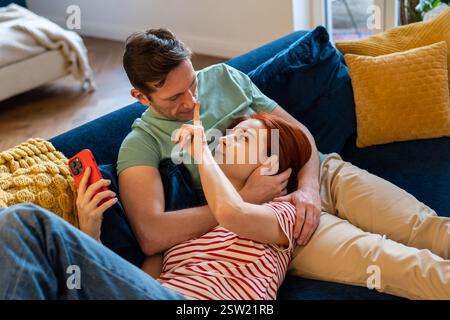 Staying connected as couple, man and woman hugging resting on sofa Stock Photo