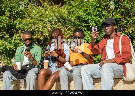 Focused on smartphones black students friends do not pay attention to each other on walk together. Stock Photo