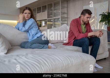 Upset quarreled married couple sitting on sofa couch in living room ignoring each other after fight Stock Photo