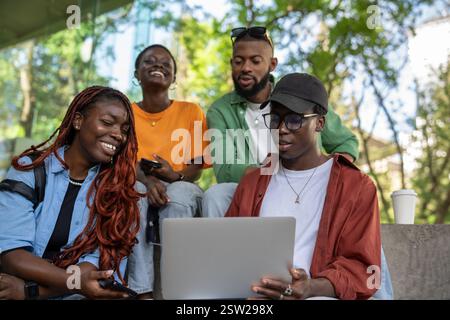 Happy cheerful group of students friends studying together with laptop outdoors with laugh and smile Stock Photo
