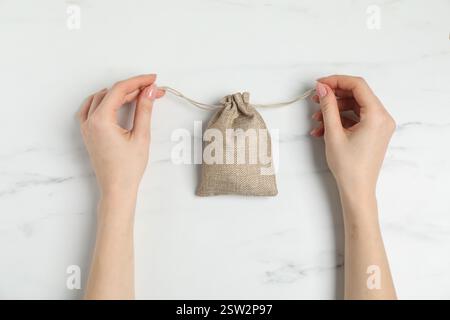 Woman with burlap bag at white marble table, top view Stock Photo