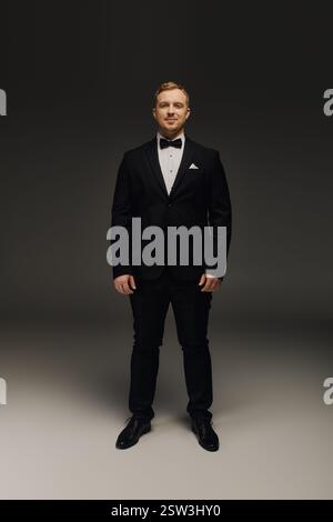 A handsome man dressed in formal attire stands poised, exuding sophistication and charm. Stock Photo
