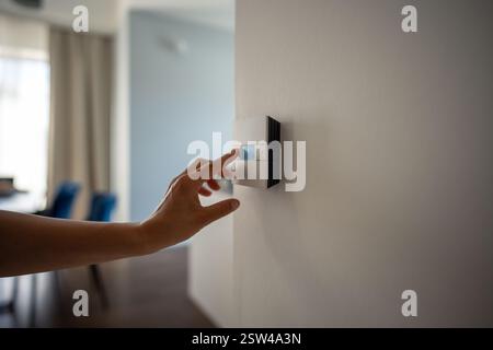 Woman hand adjusts underfloor heating settings in smart home panel for comfort in cold season Stock Photo