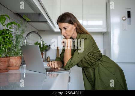 Focused female engrossed in reading of cooking receipts, choosing food, products in online shop Stock Photo
