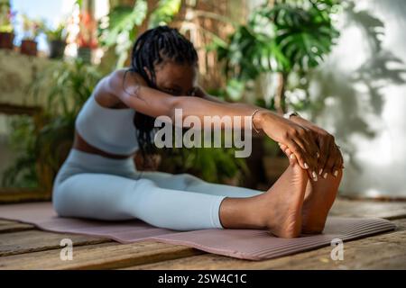 Young african american sportswoman stretching exercise warmup muscles before home fitness workout. Stock Photo