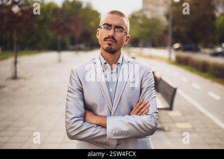Portrait of thoughtful and distraught young businessman who is standing in the street and looking at camera. Stock Photo