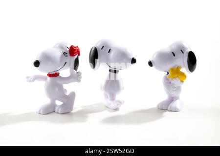 Three plastic Snoopy figurines from the popular Peanuts comic strip are standing on a white background, each one with a different expression Stock Photo