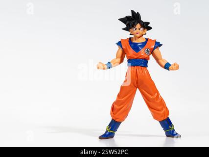 Miniature figurine of Goku, a cartoon hero from Dragon Ball standing on white background with legs apart and fists clenched, ready to fight Stock Photo