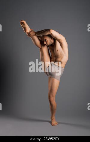 Dancer practicing a vertical leg hold pose, showcasing flexibility and strength in a studio setting Stock Photo