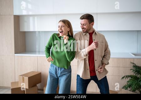 Happy loving couple have fun, dancing on moving day in new home, feels pleasure of fulfilling dream Stock Photo