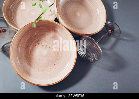 Close up of glazed ceramic soup bowls with cocktail glasses on grey background. Set of empty dishware Stock Photo