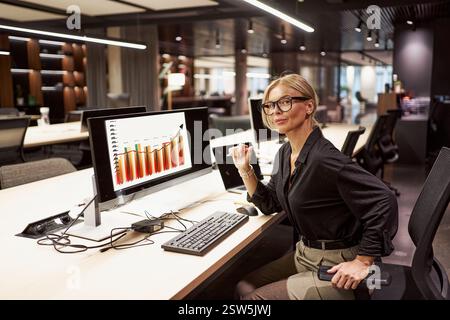 A successful businesswoman is thoroughly analyzing data within her modern office environment Stock Photo