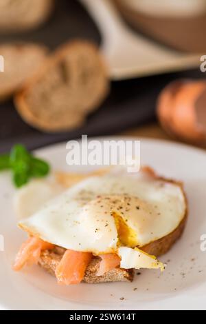 A slice of bread with lightly salted red fish and a cooked egg for breakfast. Stock Photo