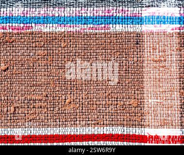 Old homespun doormat made from strips of cloth as background Stock Photo