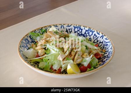 Grilled chicken salad with fresh greens lemon and cherry tomatoes Stock Photo
