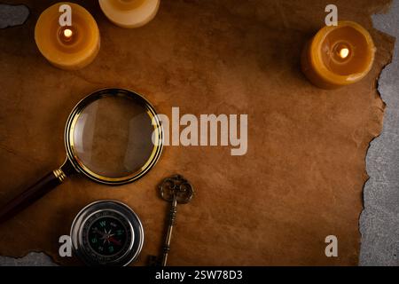Old paper, compass, magnifying glass, candles and an old key top view Stock Photo