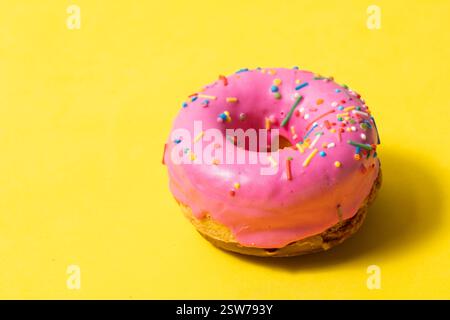Donut with pink glaze on yellow background. Closeup Stock Photo