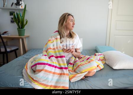 Relaxed woman in bed enjoying coffee and contemplation, resting on lazy morning, lead slow living Stock Photo