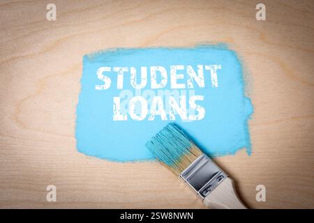 Student Loans. Blue paint and paintbrush on wooden background. Stock Photo
