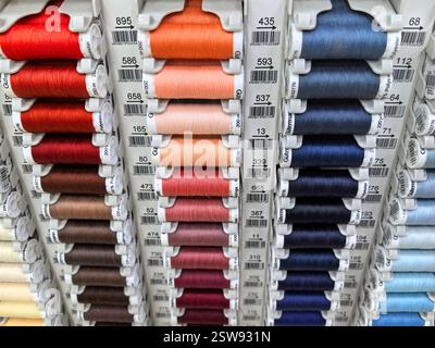 A vibrant display of neatly arranged spools of thread in various colors awaits crafters in a local craft store. Each spool signifies a world of creati Stock Photo