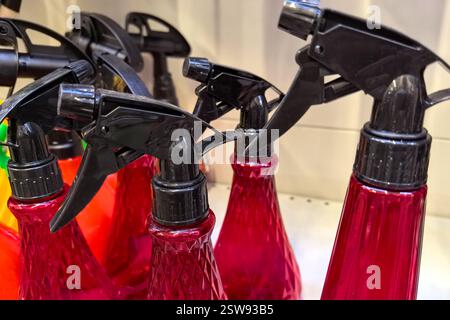 Brightly colored spray bottles with black trigger tops are lined up on a shelf in a retail space. Their vivid hues create an eye-catching arrangement Stock Photo