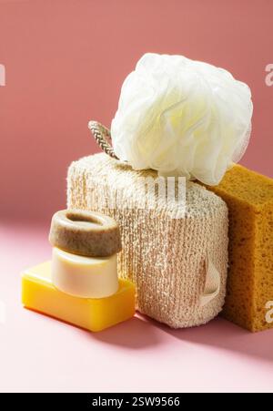 Set of bath accessories, sponges of different sizes and shapes and handmade soap on a pink background. Individual set for body skin care. Stock Photo